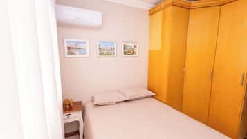 Un dormitorio con una cama, un armario, una mesita de noche y tres cuadros en la pared.