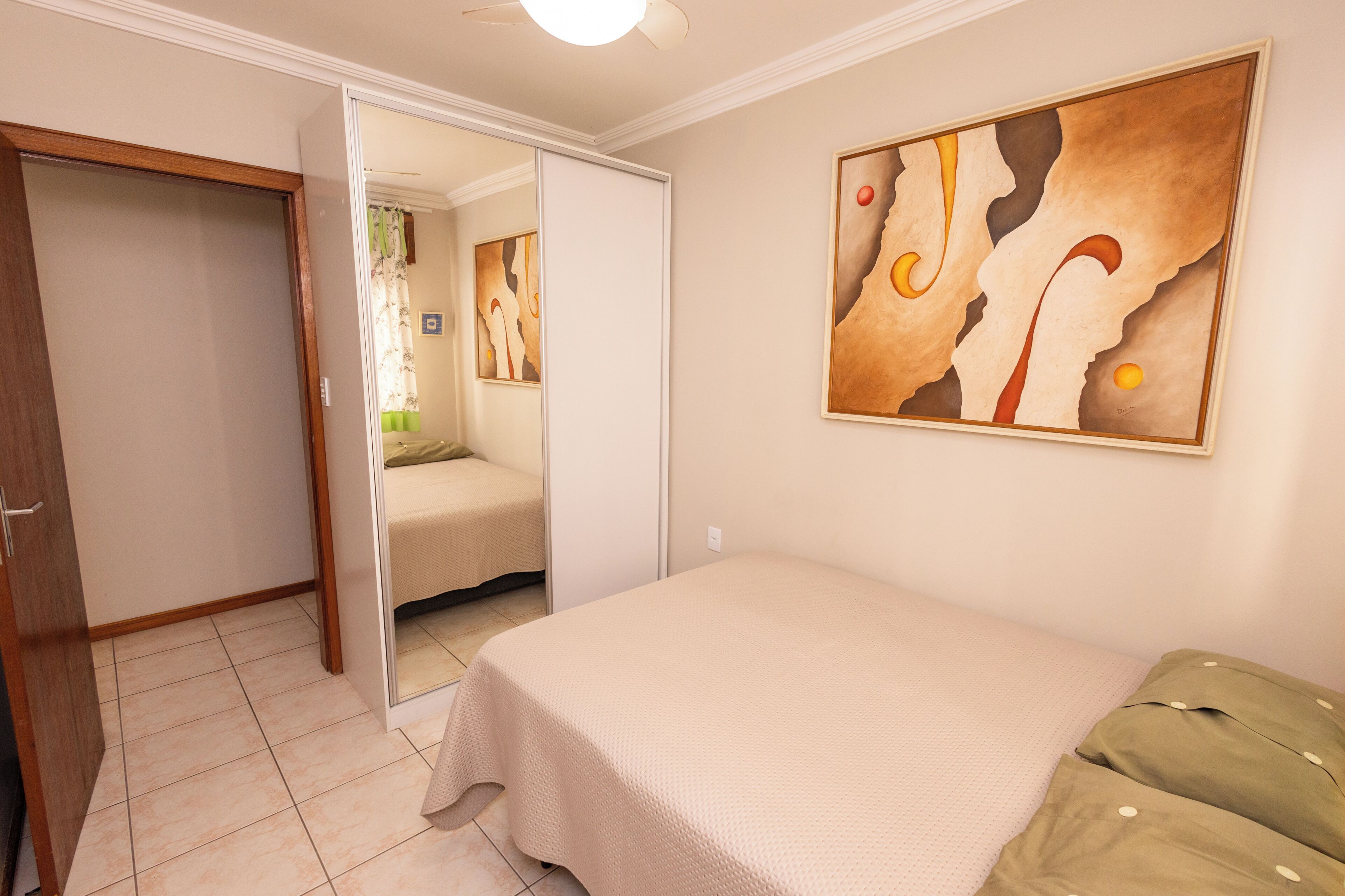 A bedroom with a bed, a wardrobe, and a painting on the wall.