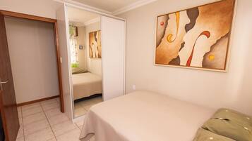 A bedroom with a bed, a wardrobe, and a painting on the wall.