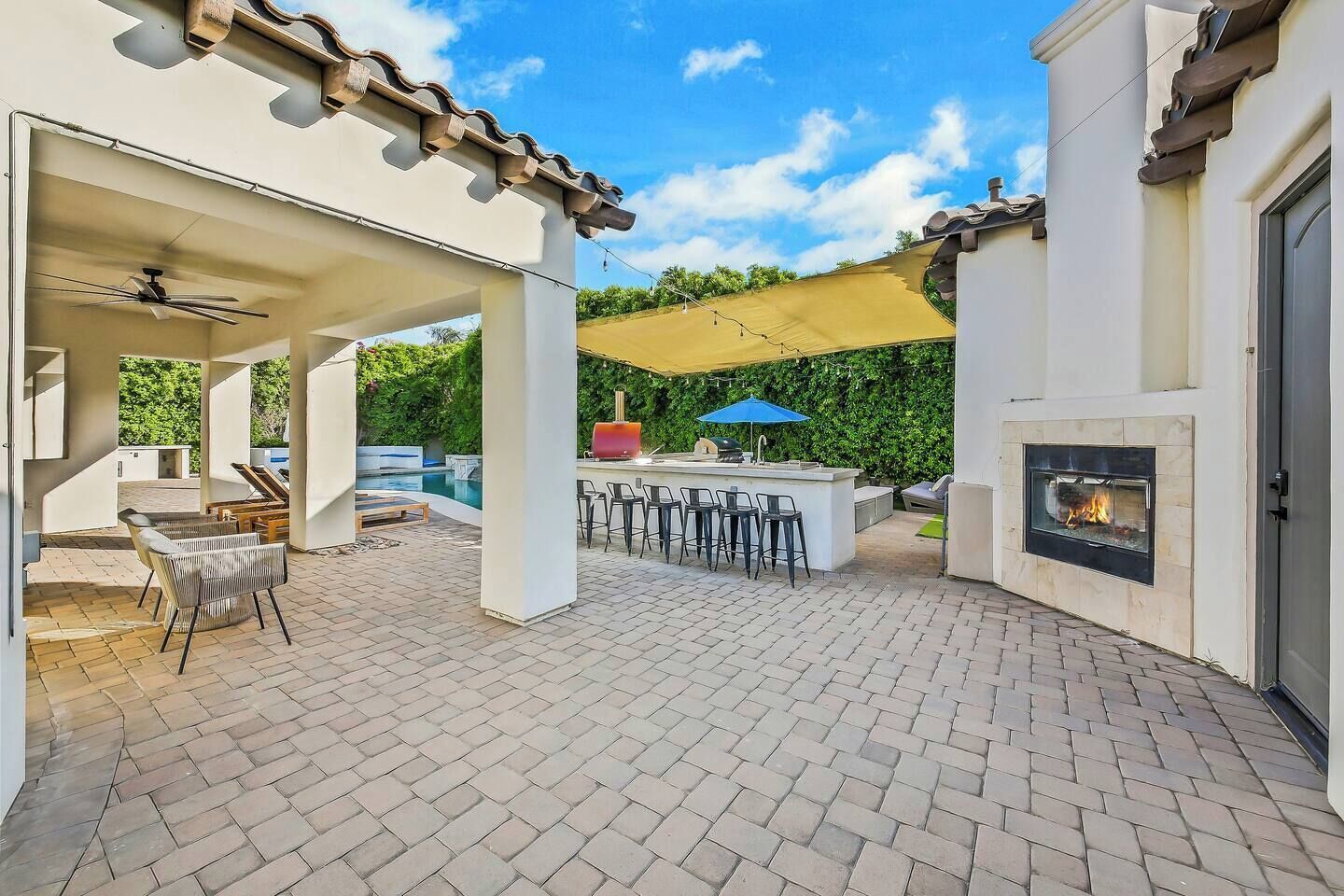 An outdoor patio with a barbecue area, seating, and a fireplace.
