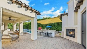 An outdoor patio with a barbecue area, seating, and a fireplace.