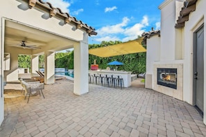 An outdoor patio with a barbecue area, seating, and a fireplace.