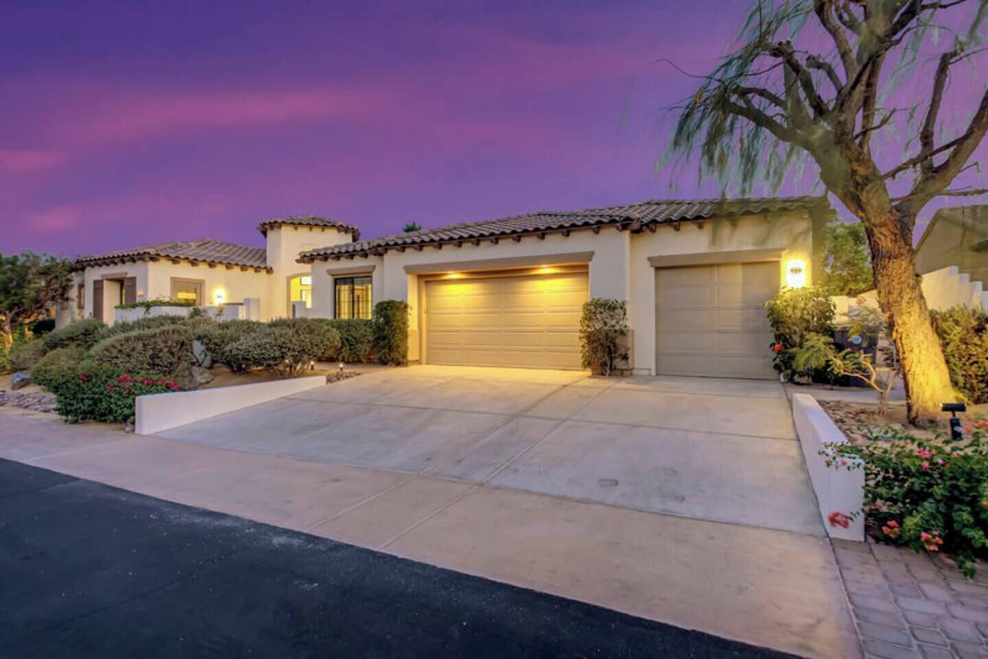 A residential property with a driveway, garage doors, and a well-maintained garden.