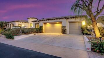 A residential property with a driveway, garage doors, and a well-maintained garden.