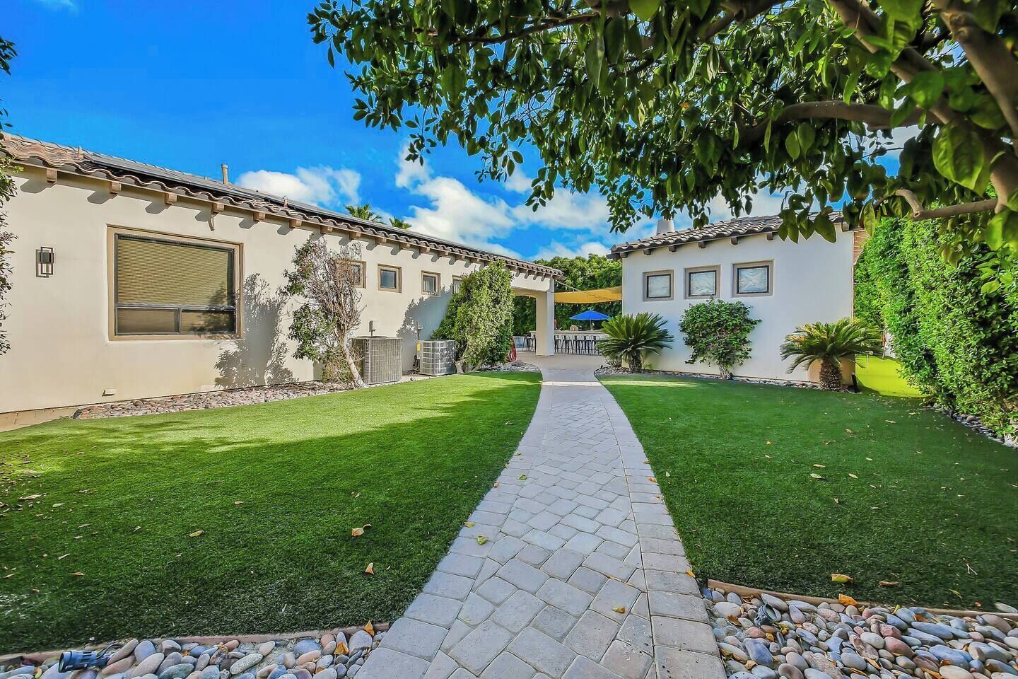 A two-story building with a paved walkway leading to a covered patio area.