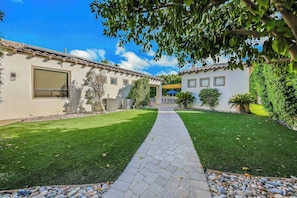 A two-story building with a paved walkway leading to a covered patio area.