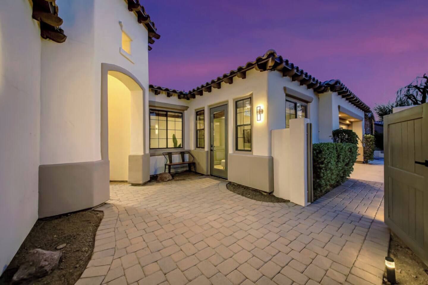 A residential property with a paved driveway, a bench, and a gated entrance.