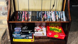 Una estantería de madera con varios juegos de mesa y una lámpara.