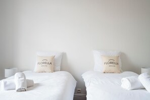 Ein Hotelzimmer mit zwei Betten, jedes mit einem Kopfkissen mit der Aufschrift 'Cannes Florence seit 1952'.