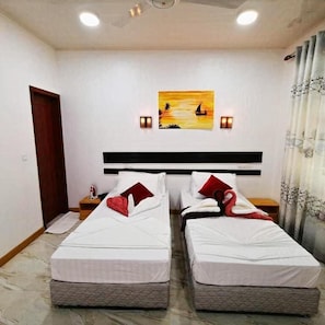 Habitación de hotel con dos camas individuales, un cuadro en la pared y un ventilador de techo.