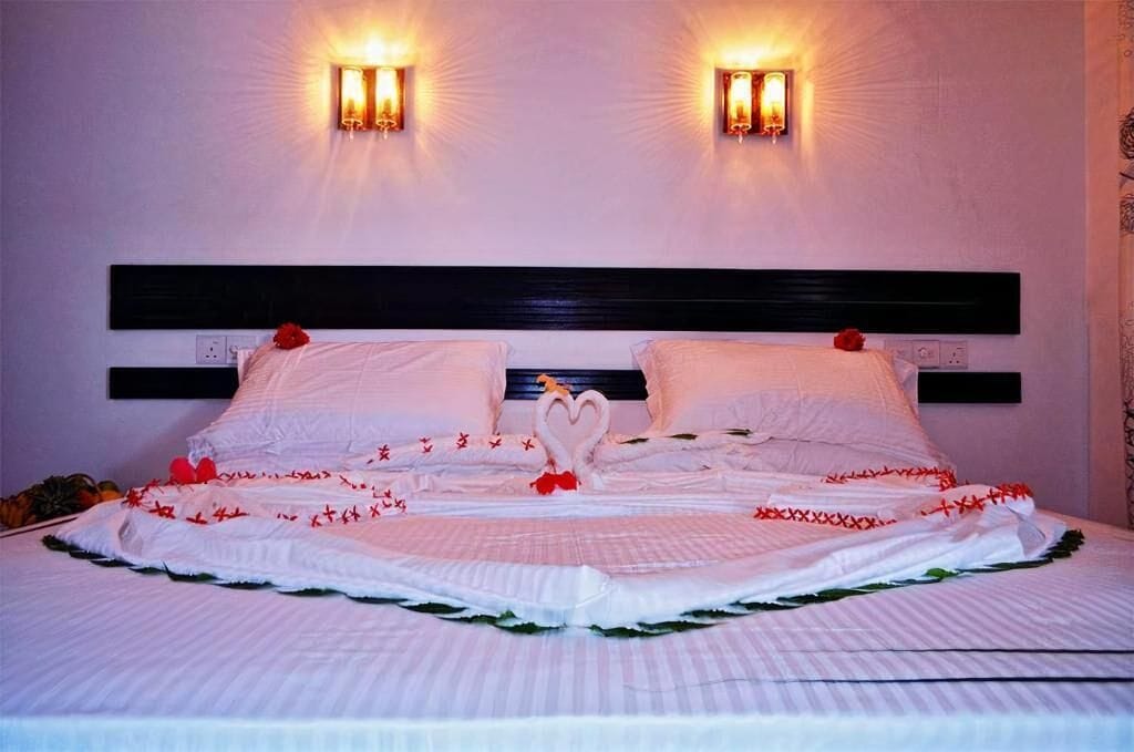 A bed with a heart-shaped centerpiece, two wall sconces, and a dark headboard.