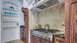 A kitchen with a gas stove, wooden cabinets, and a tiled backsplash.