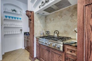 A kitchen with a gas stove, wooden cabinets, and a tiled backsplash.