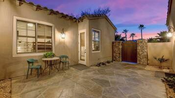 A patio with stone flooring, a table with chairs, and a gated entrance.