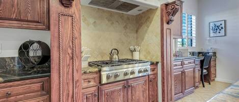 Une cuisine avec des meubles en bois, une cuisinière à gaz et un dosseret carrelé.