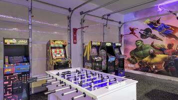 A room with a foosball table, arcade games, and a mural of comic book characters.