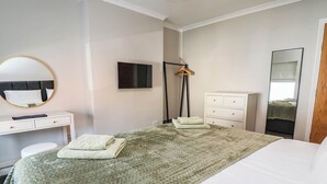 Ein Hotelzimmer mit einem Bett, einem Schreibtisch, einem Sessel, einem Schminktisch und einem Fernseher.