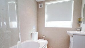 Ein Badezimmer mit Badewanne, Toilette, Waschbecken und einem Fenster.