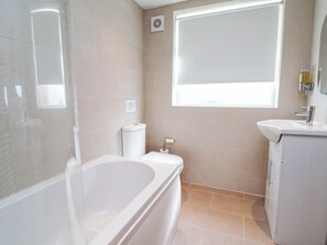 A bathroom with a bathtub, toilet, sink, and a window. - Brightside (Wirral)