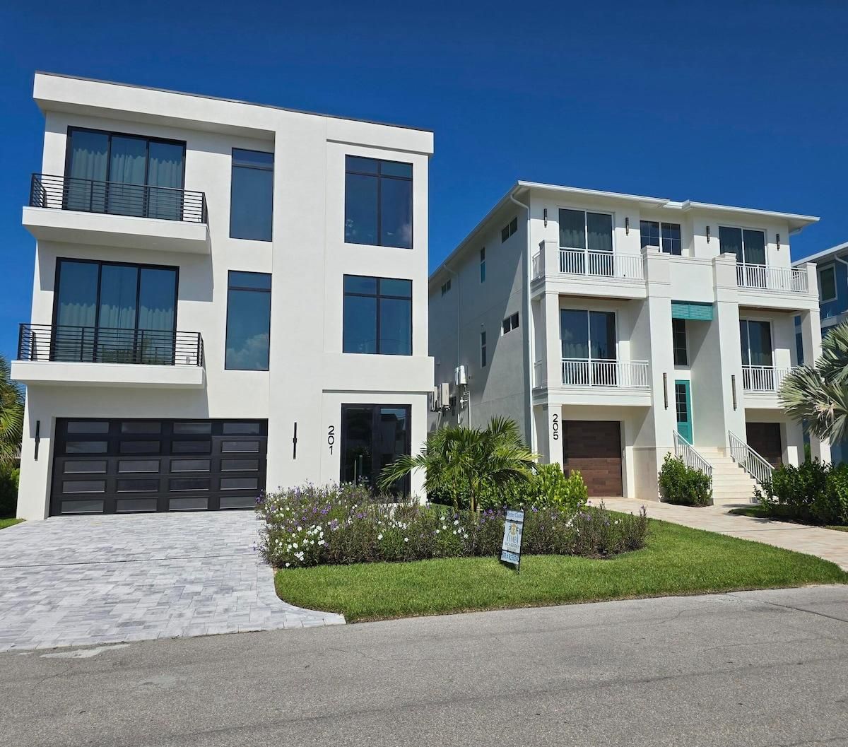 Un immeuble résidentiel moderne à deux étages, doté d’un garage, de balcons et d’une pelouse bien entretenue.