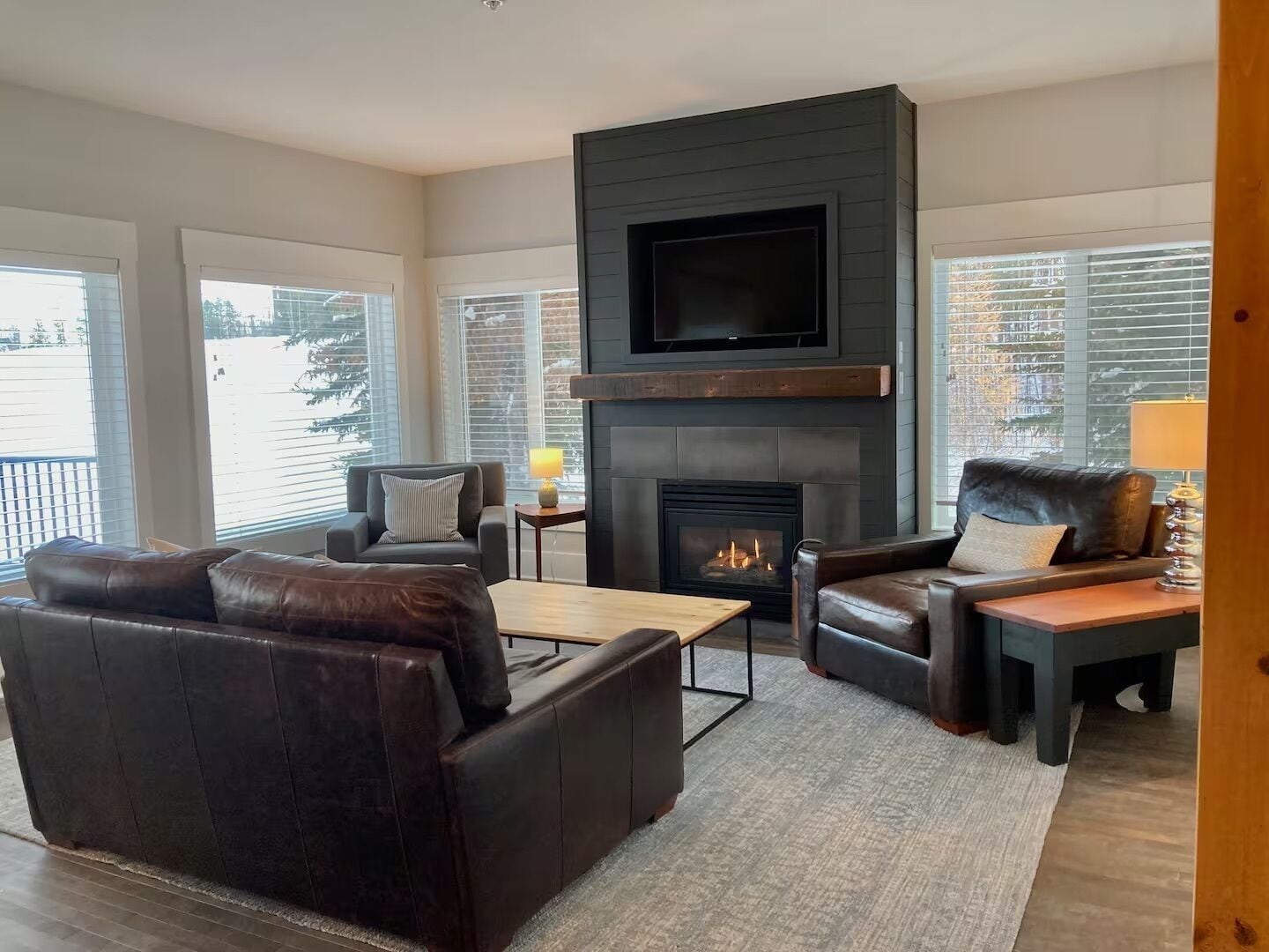 A modern living room with a fireplace, leather sofas, and a flat-screen TV mounted above the fireplace.