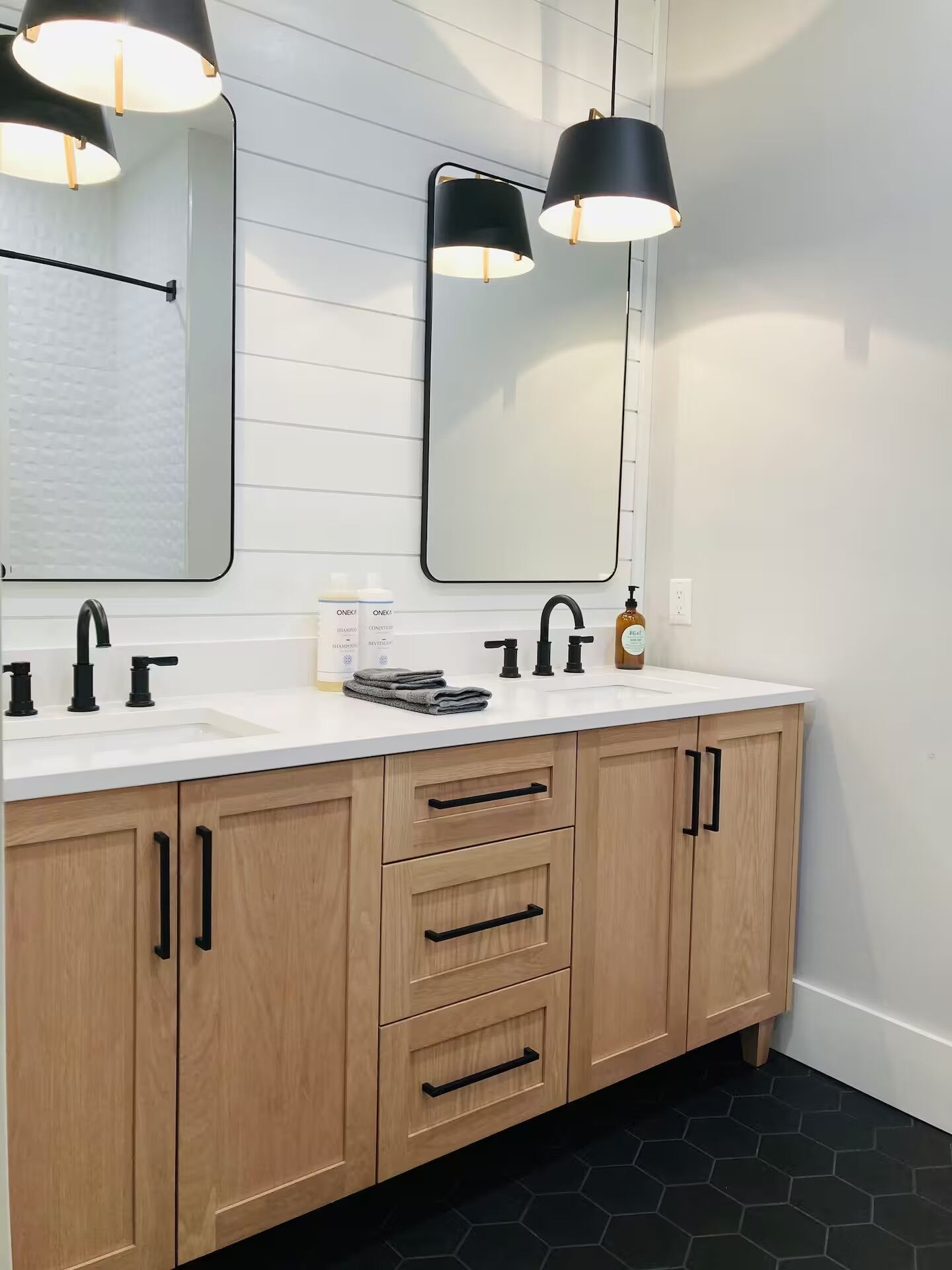 A bathroom with a white vanity, black faucets, and a mirror above the sink.