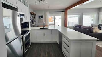 Una cocina moderna con armarios blancos, un refrigerador de acero inoxidable y una isla grande con un lavamanos.