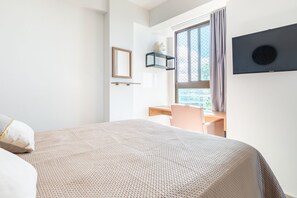 Une chambre d’hôtel moderne avec un grand lit, un bureau et une fenêtre avec des rideaux.