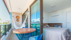 Un balcon avec un hamac, une table ronde en bois et des chaises bleues.