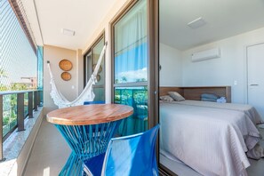 Ein Balkon mit einer Hängematte, einem runden Holztisch und blauen Stühlen.