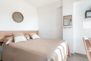 A neatly made bed with a headboard, a wall-mounted mirror, and a small shelf. - Apê Completo em Porto de Galinhas-SH164D (Ipojuca)