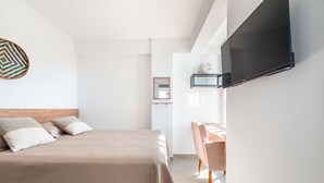 Une chambre d’hôtel moderne équipée d’un lit, d’un bureau et d’un téléviseur fixé au mur.