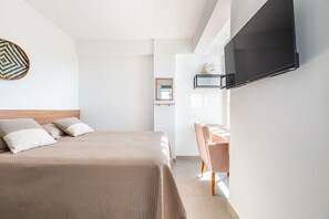 Ein modernes Hotelzimmer mit einem Bett, einem Schreibtisch und einem an der Wand befestigten Fernseher.