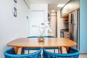 Une cuisine moderne avec un réfrigérateur en acier inoxydable, une table à manger avec des chaises bleues et des orchidées blanches disposées sur la table.