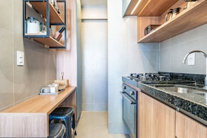 A modern kitchen with wooden cabinetry, a granite countertop, and stainless steel appliances. - Apê Completo em Porto de Galinhas-SH164D (Ipojuca)