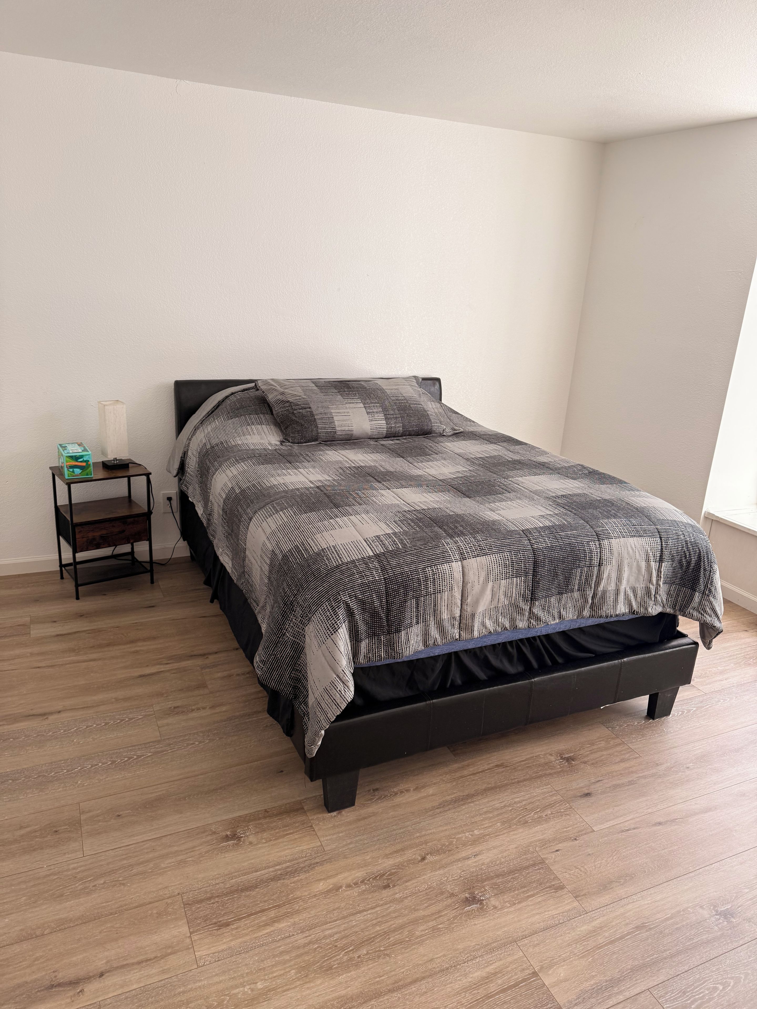 Une chambre à coucher avec un lit, une table de chevet et une fenêtre.