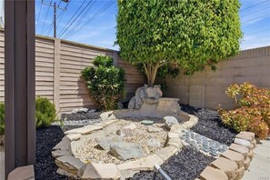 Un jardin aménagé avec une variété de plantes, un sentier en pierre et une clôture en bois.