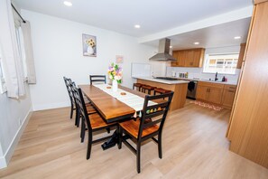 Une cuisine moderne avec des meubles en bois, un îlot central et un coin repas comprenant une table et des chaises en bois.
