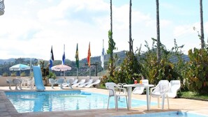 Zona de piscina con sillas de descanso, sombrillas y banderas.