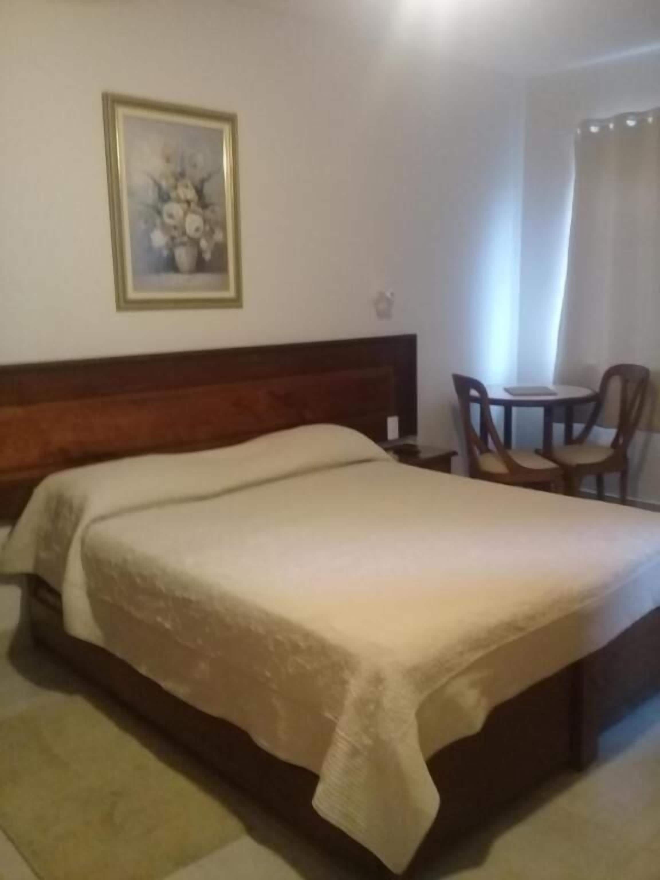Una habitación de hotel con una cama, una mesita pequeña y una silla.
