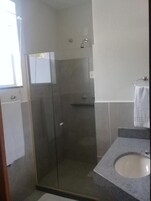 Un baño moderno con cabina de ducha de vidrio, un lavamanos y un perchero para toallas.