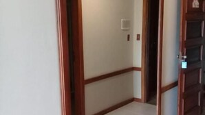 Un pasillo con un espejo de marco de madera, suelo de baldosas y una puerta que da a otra habitación.