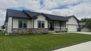 A two-story house with a stone foundation, a front porch, and a garage.