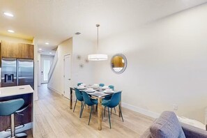 A modern kitchen with a dining area, a staircase, and a wall-mounted mirror. - Family Pool Home Near Disney Parks & Golf Fun (Clermont)