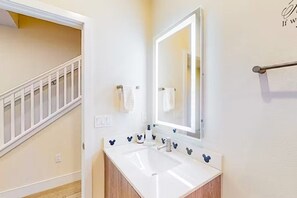 A bathroom with a white sink, mirror, and Mickey Mouse decorations. - Family Pool Home Near Disney Parks & Golf Fun (Clermont)