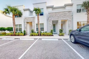 A modern building with a parking lot, palm trees, and a car. - Family Pool Home Near Disney Parks & Golf Fun (Clermont)