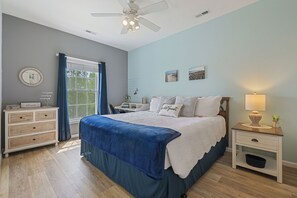 A bedroom with a bed, a nightstand, a dresser, a ceiling fan, and a window with curtains. - Stress-Free Family Beach Stay, Pool + Perks in Rehoboth Beach (Rehoboth Beach)