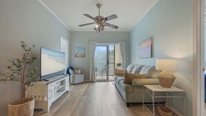 Ein Wohnzimmer mit Fernseher, Sofa und Deckenventilator.
