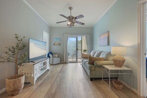 A living room with a television, sofa, and a ceiling fan. - Stress-Free Family Beach Stay, Pool + Perks in Rehoboth Beach (Rehoboth Beach)