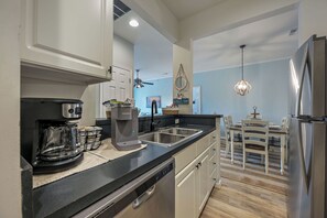 A modern kitchen with a coffee maker, dishwasher, and stainless steel appliances. - Stress-Free Family Beach Stay, Pool + Perks in Rehoboth Beach (Rehoboth Beach)